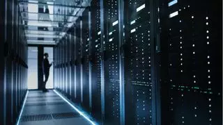 Technology tamfitronics A person standing in front of a rack of servers inside a data center