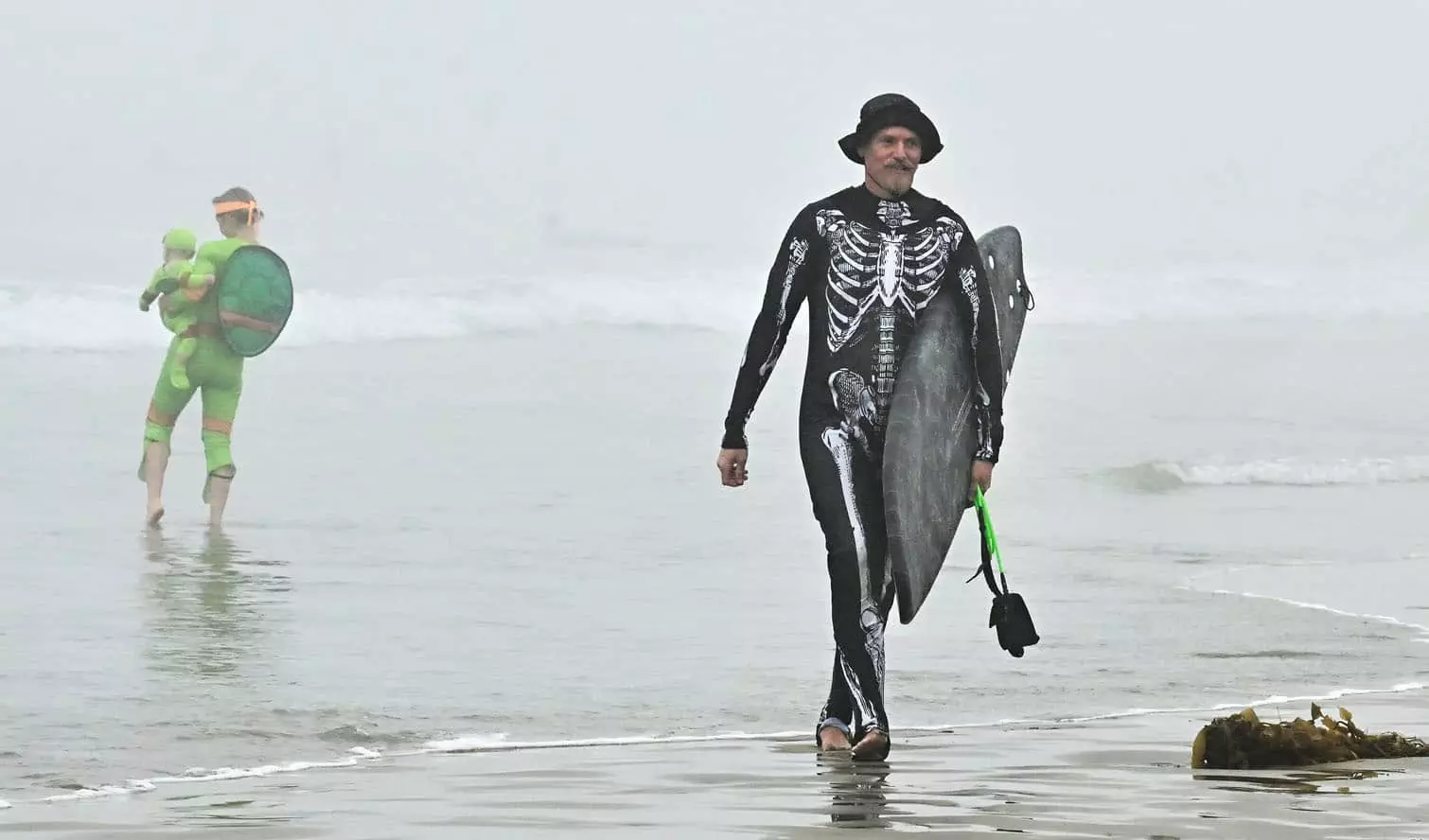 Top Stories Tamfitronics Surfers arrive in costume to surf the waves on a foggy morning at Newport Beach