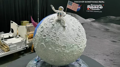 NASA Space Technology closeup of a spherical cake that looks like the moon, with a spacesuit-wearing astronaut on it